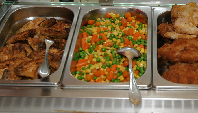 Buffet mit Fleisch und Gemüse in Warmhaltebehältern.