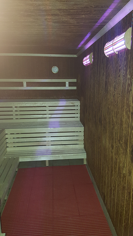 Sauna von der anderen Seite, Holzbänke und Wandlampen.